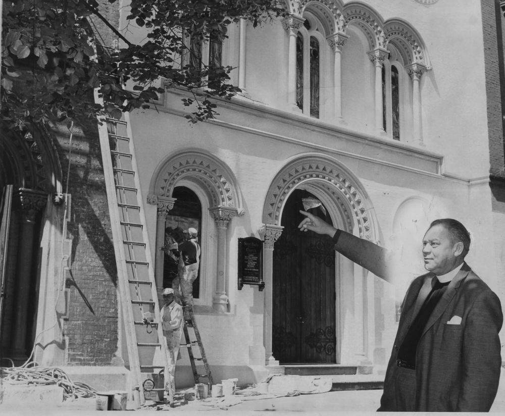 Recently appointed Rector Rev. Nelson F. Parke proudly points to the newly painted St. Paul's, 9 July 1960.  Times Union staff photo taken by Wilder. Used by permission of the Times Union.